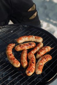 Close-up of delicious sausages grilling over charcoal, perfect for summer barbecues.
