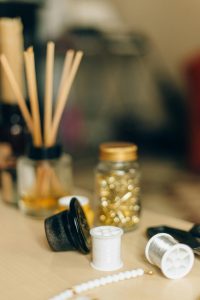 A close-up of crafting supplies, including thread, beads, and essential tools, on a wooden table.